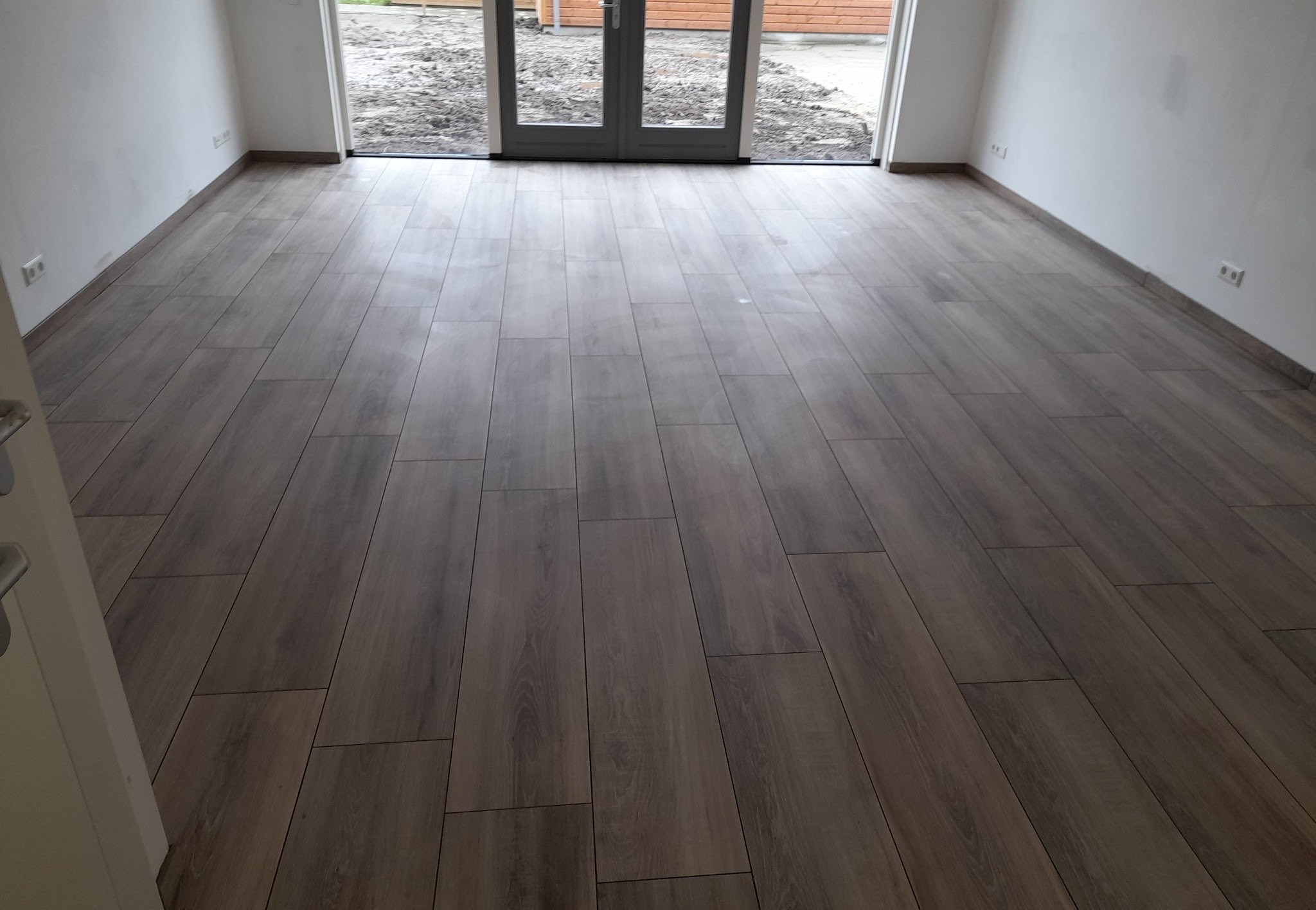 Houtlook tegelvloer in een woonkamer met openslaande tuindeuren